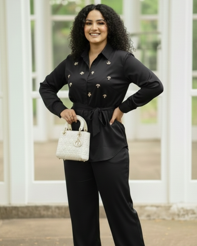 Woman in a black outfit holding a white handbag outdoors.
