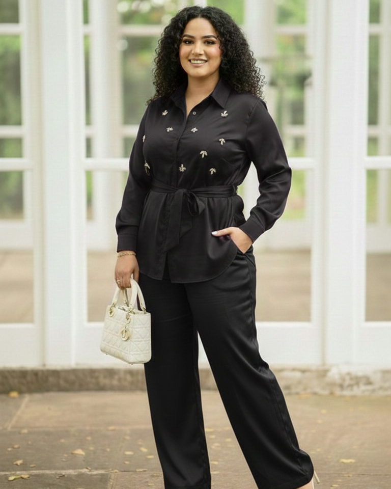 Woman in a black outfit standing in front of a glass paneled wall.