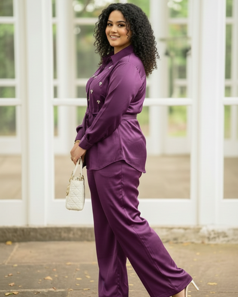 Woman in a purple outfit standing outdoors with a white lattice background