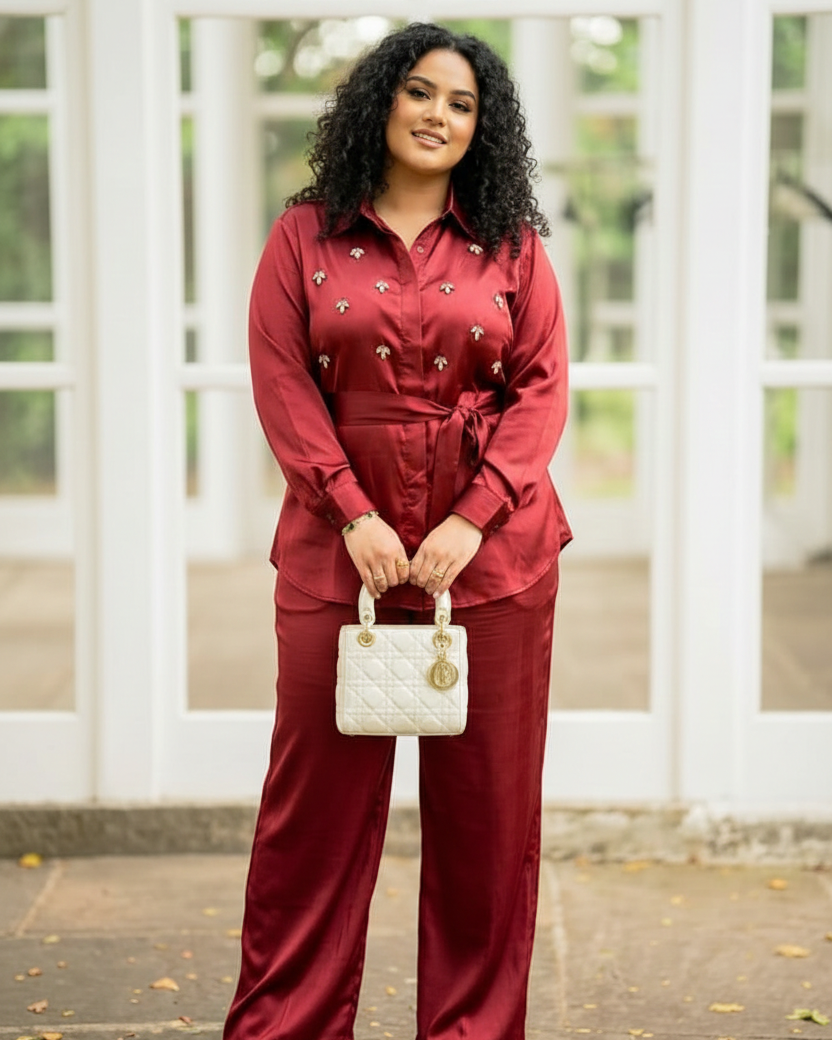 Woman in a red outfit holding a white handbag in front of a white lattice background
